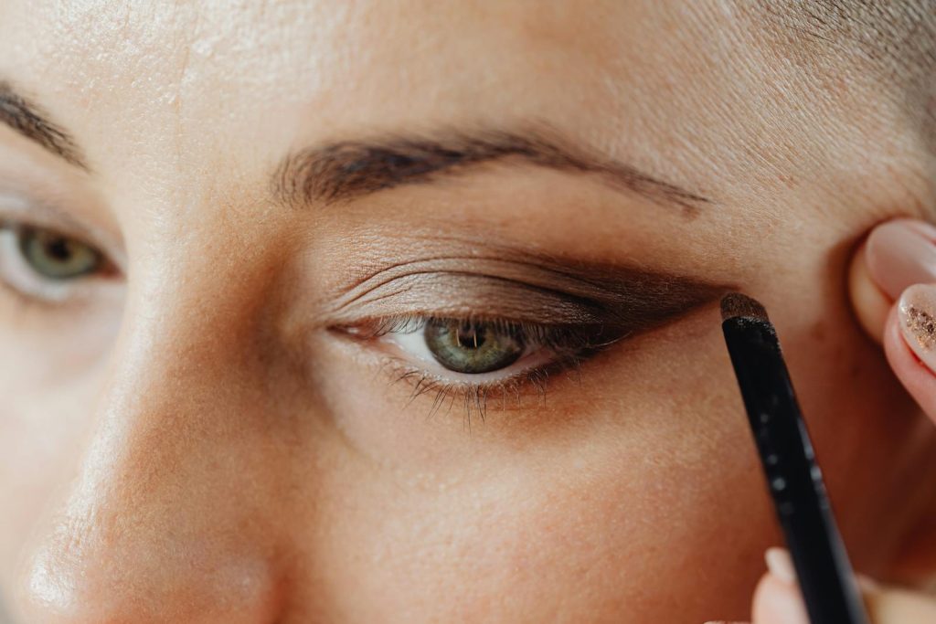 A detailed close-up of a woman applying eyeshadow using a makeup brush, highlighting the eye area.